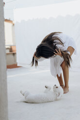 Junge Frau spielt mit ihrem Hund auf der Dachterrasse - AFVF01407