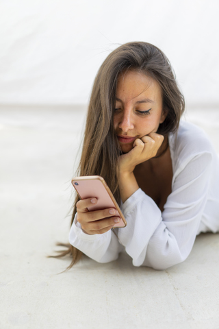 Porträt einer jungen Frau, die auf ein Mobiltelefon schaut, lizenzfreies Stockfoto