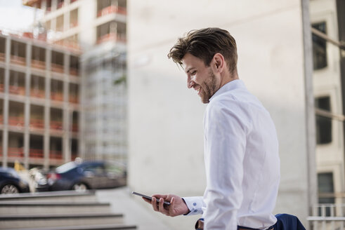 Geschäftsmann steht in der Stadt und benutzt ein Mobiltelefon - DIGF04883