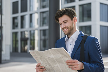 Smiling businessman reading newspaper in the city - DIGF04899