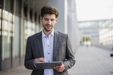 Smiling businessman in the city using tablet - DIGF04932