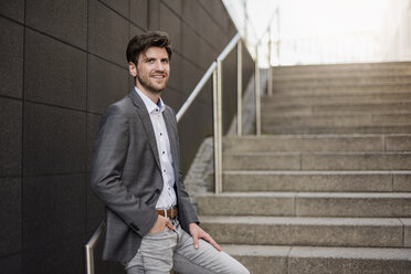 Smiling businessman standing on stairs - DIGF04938