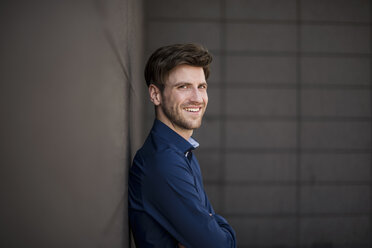 Portrait of smiling businessman at a wall - DIGF04952