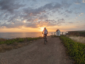 Portugal, Alentejo, älterer Mann auf E-Bike bei Sonnenuntergang - LAF02070