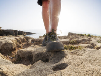 Älterer Mann mit Wanderschuhen auf einem Felsen stehend, gegen die Sonne - LAF02072