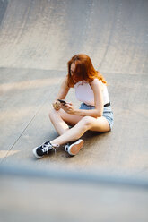 Redheaded woman using smartphone outdoors - GIOF04195