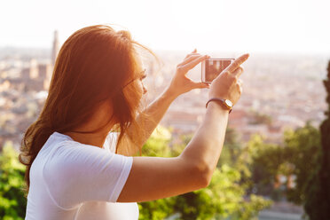 Italien, Verona, Italien, Verona, rothaarige Frau fotografiert mit Smartphone bei Sonnenuntergang - GIOF04218