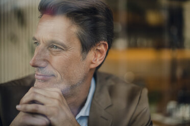 Mature businessman sitting in coffee shop, looking out of window - GUSF00983