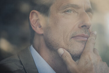 Mature businessman sitting in coffee shop, looking out of window - GUSF00988