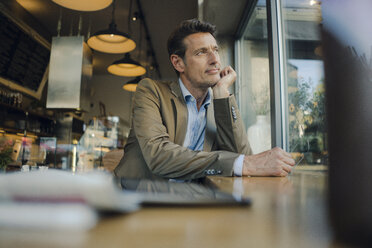 Mature businessman sitting in coffee shop, looking out of window - GUSF00993