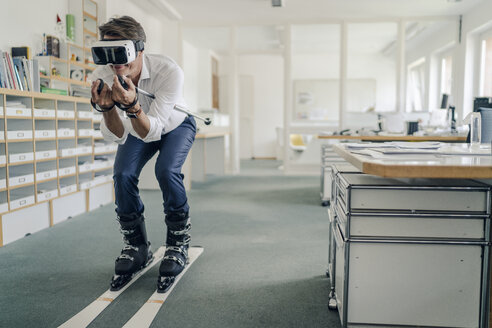 Businessman skiing in office, using VR glasses - GUSF00998