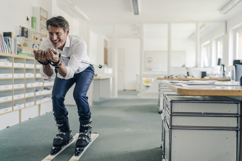 Businessman skiing in office - GUSF01011