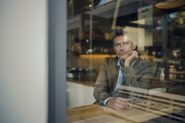 Mature businessman sitting in coffee shop, smiling - GUSF01029