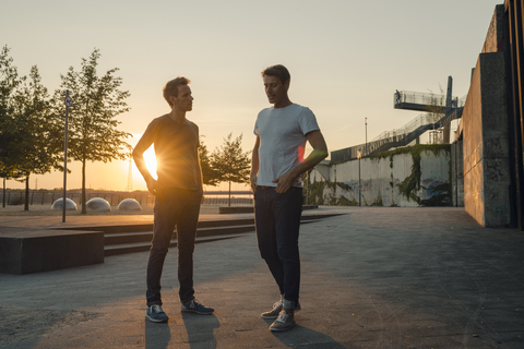 Two friends meeting at sunset, spending the evening talking stock photo