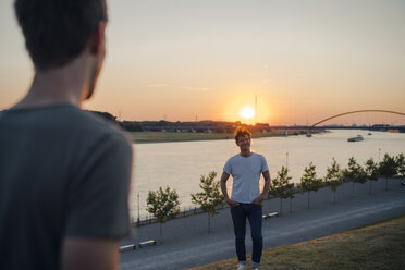 Zwei Freunde beobachten den Sonnenuntergang am Fluss - GUSF01043