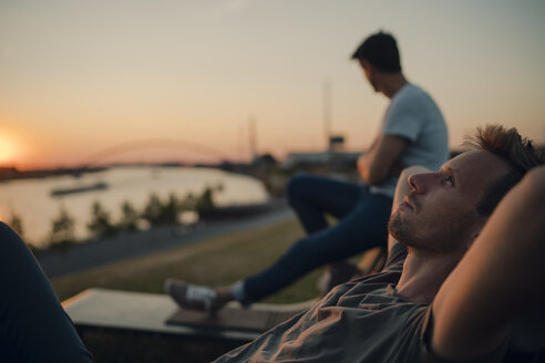 Zwei Freunde beobachten den Sonnenuntergang am Fluss - GUSF01045