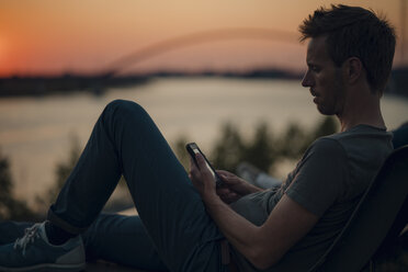 Man using smartphone at sunset - GUSF01047