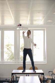 Businessman playing with inflatable airplane in office - GUSF01049