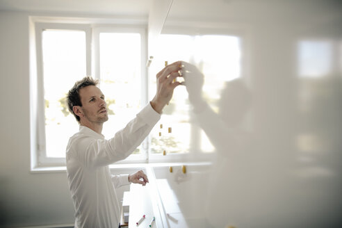 Businessman preparing whiteboard for a meeting - GUSF01053