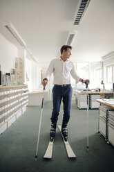 Businessman skiing in office - GUSF01084