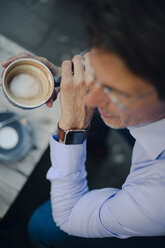 Älterer Geschäftsmann sitzt in einem Café und trägt eine intelligente Uhr - GUSF01105
