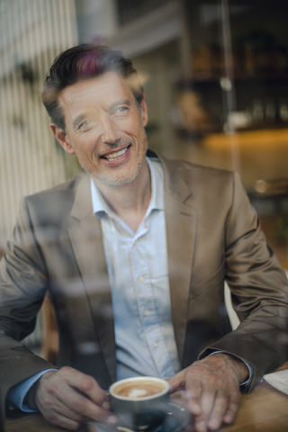 Älterer Geschäftsmann sitzt in einem Café und lächelt, lizenzfreies Stockfoto