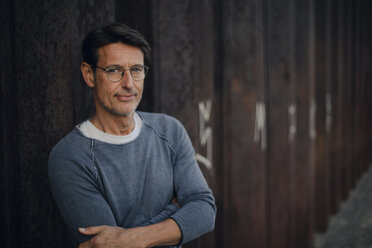 man in front of metal wall with arms crossed, portrait - GUSF01124