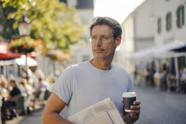 Älterer Mann geht in der Stadt mit Zeitung und digitalem Tablet spazieren, trinkt Kaffee - GUSF01154