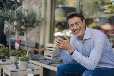 Mature businessman sitting in coffee shop, drinking coffee - GUSF01156