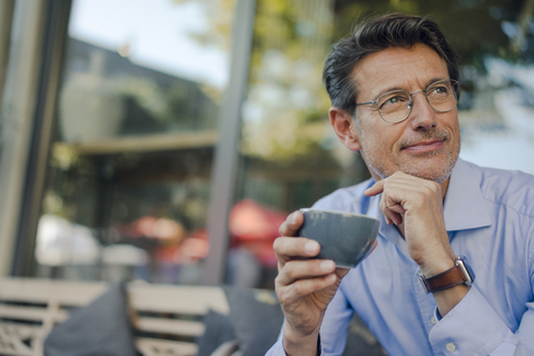 Älterer Geschäftsmann sitzt in einem Café und trinkt Kaffee, lizenzfreies Stockfoto