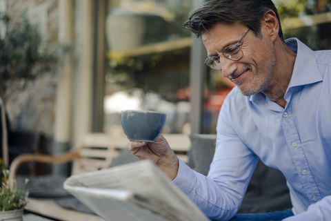 Älterer Geschäftsmann sitzt in einem Café und trinkt Kaffee, lizenzfreies Stockfoto