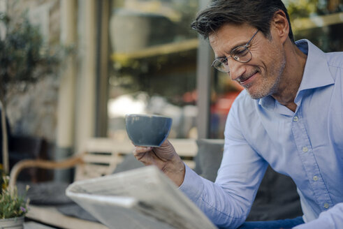 Mature businessman sitting in coffee shop, drinking coffee - GUSF01159