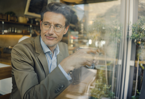 Älterer Geschäftsmann sitzt in einem Café und trinkt Kaffee, lizenzfreies Stockfoto