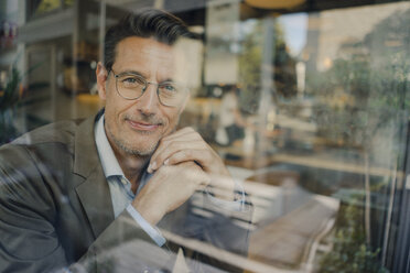 Mature businessman sitting in coffee shop, looking out of window - GUSF01162