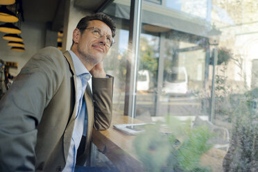 Mature businessman sitting in coffee shop, looking out of window - GUSF01163