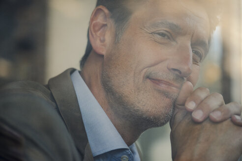 Mature businessman sitting in coffee shop, portrait - GUSF01165