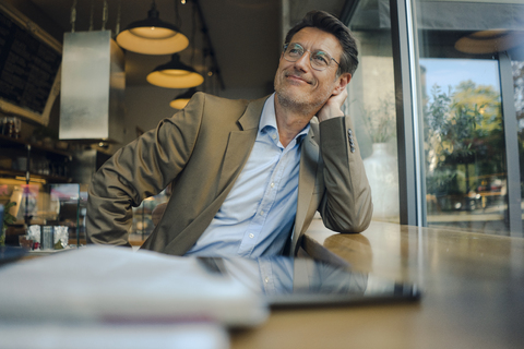 Mature businessman sitting in coffee shop, smiling stock photo
