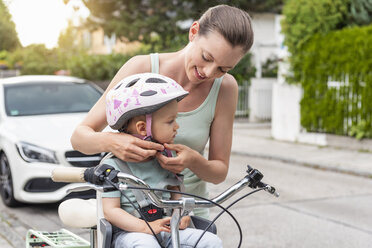 Mutter und Tochter, die Tochter trägt einen Helm und sitzt im Kindersitz - DIGF04955