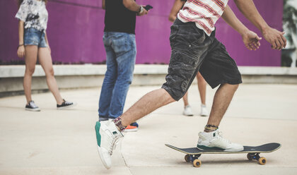 Close up of a group of people standing in a skate park and riding skateboards. - MINF08572