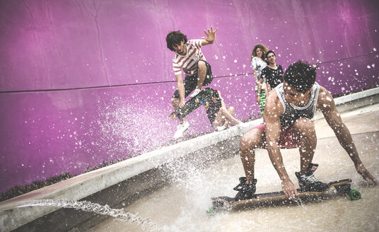 Ein Skateboarder, der in die Hocke geht, um durch das Wasser zu skaten. - MINF08577