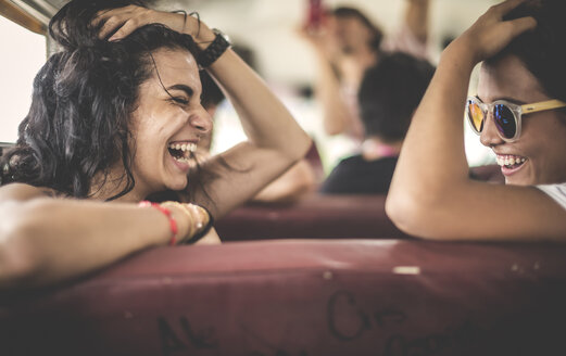 Zwei junge Frauen, Freundinnen, die zusammen in einem Schulbus lachen. - MINF08598