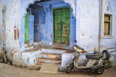 Vor einem traditionellen Gebäudeeingang in Rajasthan, Indien, geparkter Motorroller. - MINF08636