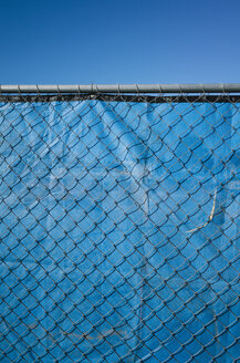 Blue fabric behind chainlink fence, blue sky above. - MINF08686