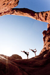 Paar in Tänzerpose (Yoga) unter dem Turmbogen im Arches National Park. - AURF00552