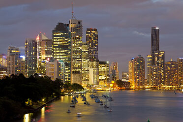 Skyline der Stadt am Meer in der Abenddämmerung, mit beleuchteten Wolkenkratzern, Segelbooten, die an der Promenade festgemacht sind. - MINF08749