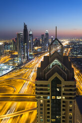 Cityscape with illuminated skyscrapers and light trails on highways at dusk. - MINF08791