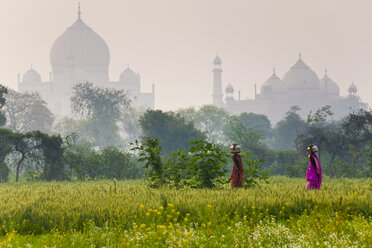 Außenansicht des Taj Mahal in Agra, Indien, mit zwei Frauen im Vordergrund, die Lasten auf ihren Köpfen tragen. - MINF08812