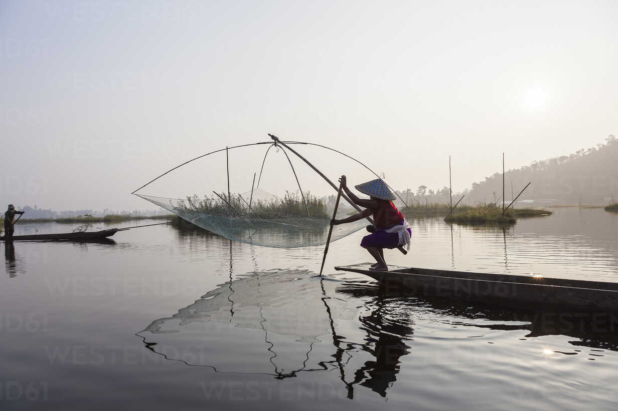 Fisherman on traditional fishing boat with net on a lake. stock photo