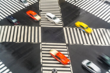 Blick aus hohem Winkel auf Autos, die auf einer städtischen Straße über Fußgängerüberwege fahren. - MINF08819