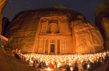 Außenansicht der in Fels gehauenen Architektur von Al Khazneh oder der Schatzkammer in Petra, Jordanien, mit einer großen Gruppe von Menschen, die nachts auf dem Boden sitzen. - MINF08822